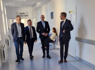 4 mężczyzn idzie szpitalnym korytarzem 