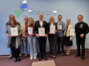 zdjęcie grupowe z NGO, częśdc osób trzyma umowy w rekach 