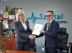od lewej: wicemarszałkini Anna Bańkowska i dyrektore szpitala przekazuja sobie umowę,znajdują się w gabinecie dyrektora szpitala