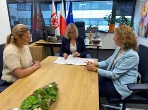 Podpisanie umowy w gabinecie wicemarszałkini. Za stołem siedzą trzy kobiety uczestniczące w spotkaniu