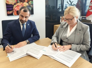 Sygnatariusze podpisują umowę przy stole prezydialnym, w tle wyposażenie gabinetu, flagi - fot. Starostwo Powiatowe w Policach.