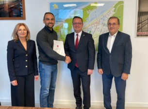 Sygnatariusze porozumienia prezentują podpisaną umowę, w tle mapa Międzyzdrojów.