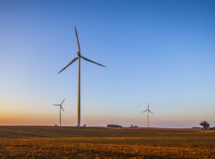 pole, na którym stoją trzy elektrownie wiatrowe (wiatraki), zdjęcie po zachodzie słońca 