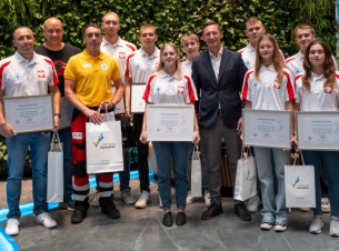 ratownicy wodni i marszałek na wspólnym zdjeciu, w tle zielona ścianka w Urzędzie Marszałkowskim. 