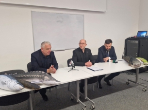 podpisanie umowy, za stołem siedzi trzech mężczyzn, w środku wicemarszałek Kowalik