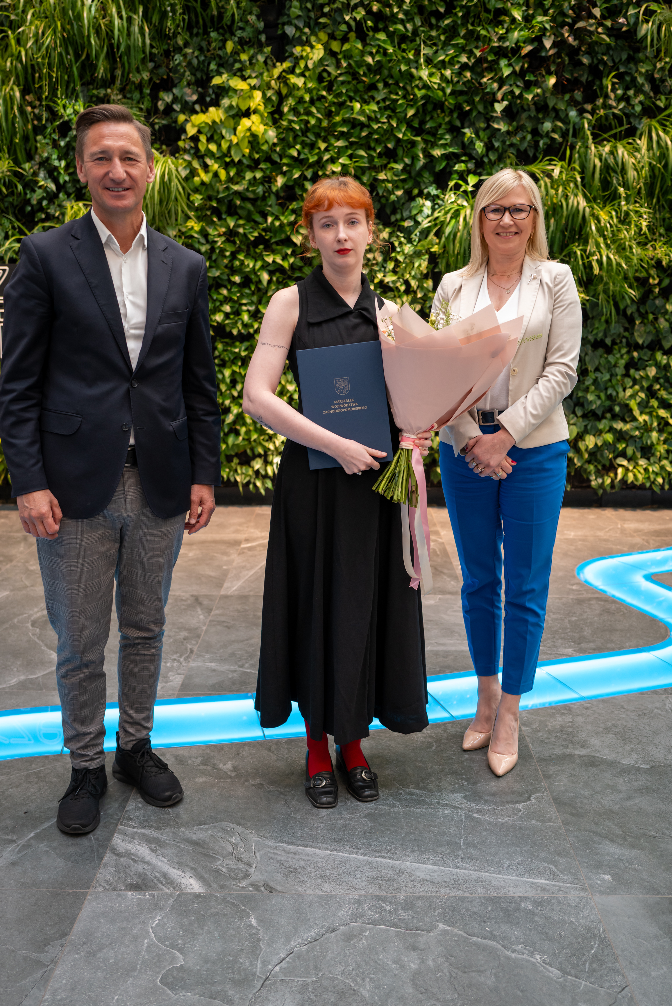 Marszałek i wicemarszałkini stoją z stypendystką