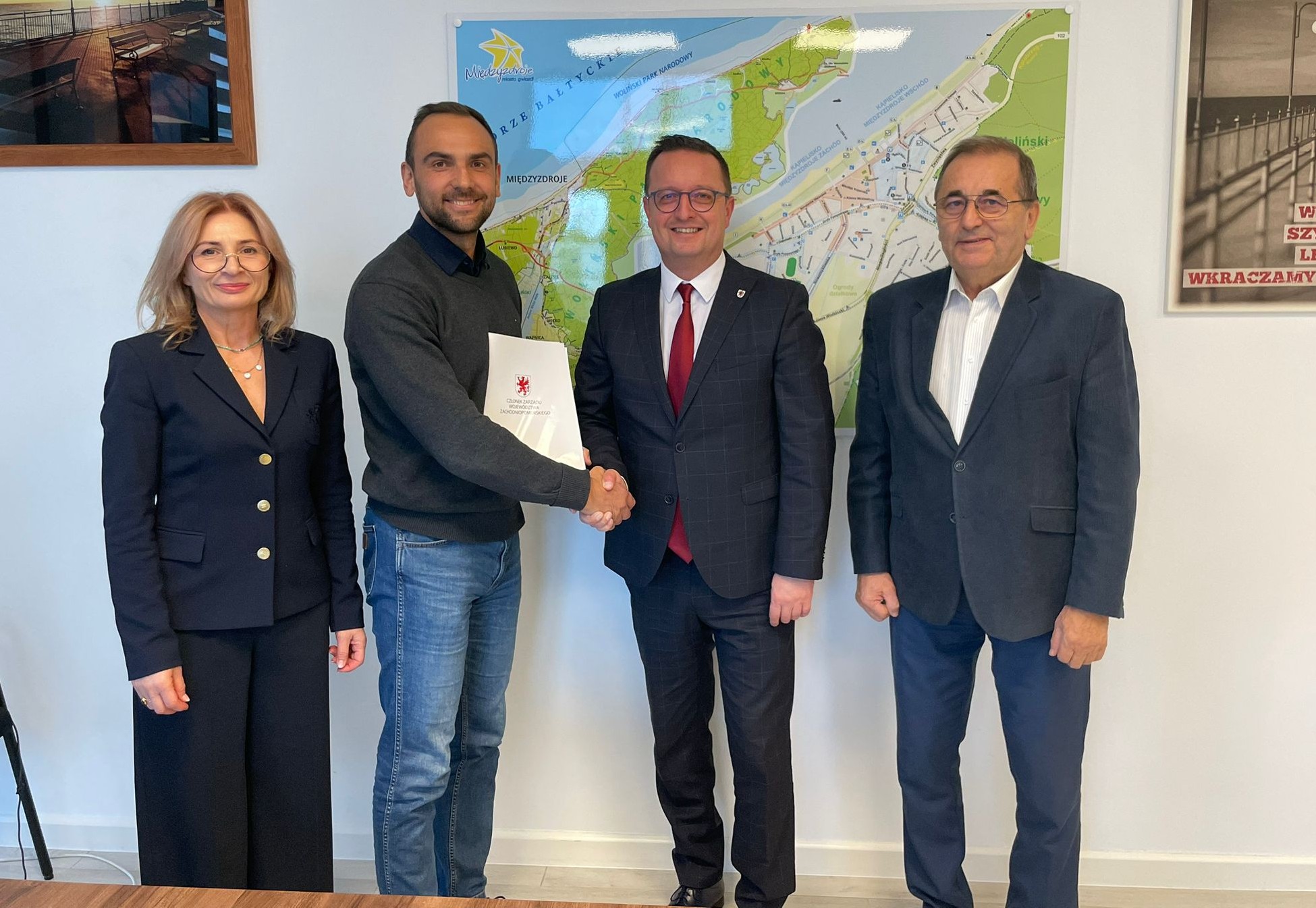 Sygnatariusze porozumienia prezentują podpisaną umowę, w tle mapa Międzyzdrojów.