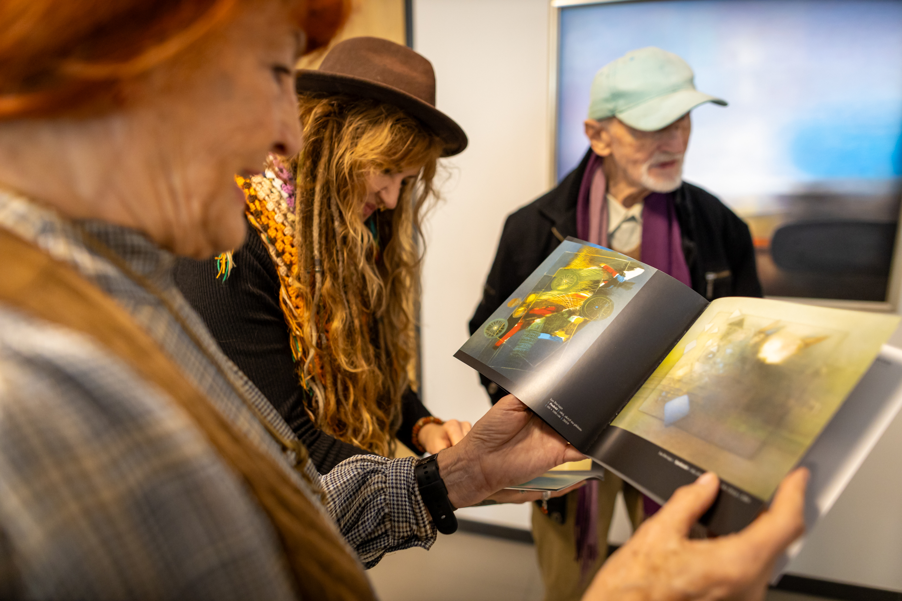 uczestnicy wernisażu przeglądają katolog obrazów Jana Bociągi